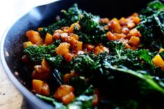 a pan filled with cooked vegetables on top of a wooden table