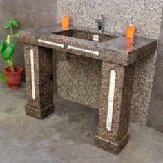 a bathroom sink sitting next to a plant in a tiled wall mounted above it's counter