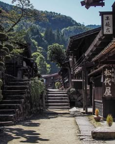 an alley way with steps leading up to the top and trees on both sides, surrounded by mountains