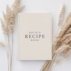 a book with the words kate's recipe book on it next to some dry grass