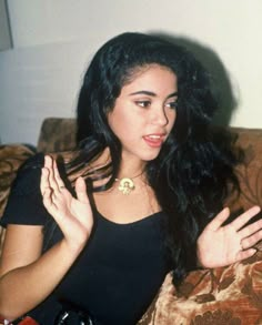 a woman sitting on top of a couch holding her hands out in front of her