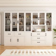 a kitchen with white cabinets and wood flooring next to a plant in a vase