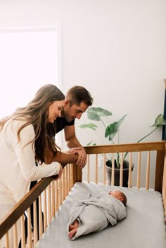 a man and woman looking at a baby in a crib