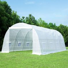 an image of a large greenhouse in the grass with trees and blue sky behind it