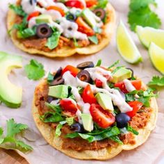 two tortillas topped with lettuce, tomatoes, black olives and avocado