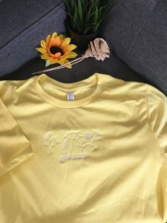 Beautiful heather yellow cotton t-shirt embroidered with Jesus flowers Summer Crew Neck T-shirt With Floral Embroidery, Summer Floral Embroidered Crew Neck T-shirt, Summer Cotton Tops With Embroidered Logo, Summer Cotton Top With Embroidered Logo, Casual Yellow T-shirt With Embroidered Graphics, Casual Yellow Tops With Embroidered Graphics, Yellow Crew Neck Top With Floral Embroidery, Yellow Embroidered Short Sleeve T-shirt, Relaxed Fit T-shirt With Embroidered Logo For Summer