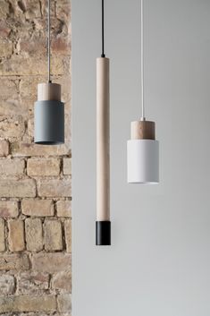 three different types of light fixtures hanging from the ceiling in front of a brick wall