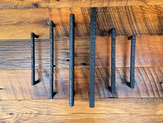 three metal handles on a wooden wall with wood planks in the background and one is black