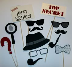 a group of photo props that say top secret, happy birthday and hipster hats