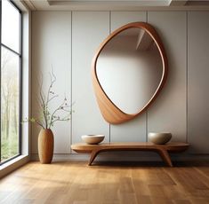 a wooden table sitting in front of a round mirror on the side of a wall