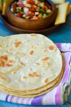 three tortillas sitting on top of a table next to a bowl of salsa