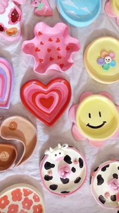 there are many different types of doughnuts on the table with hearts and smiley faces