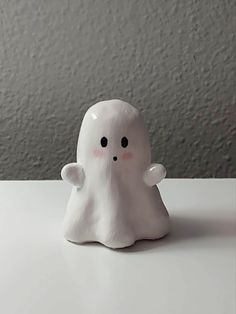 a small white ghost figurine sitting on top of a table next to a wall