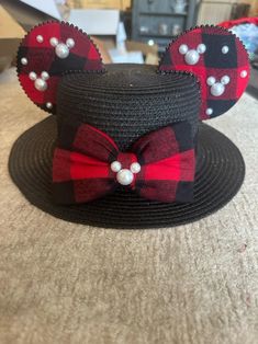 a mickey mouse hat with red and black plaid bows on it, sitting on top of a table