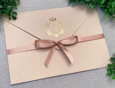 an envelope with a ribbon tied around it and a monogrammed seal on the front