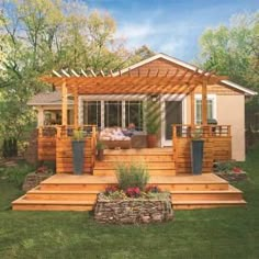 a wooden deck in front of a house with potted plants and flowers on it