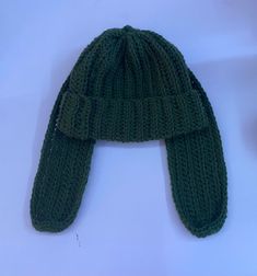 a green knitted hat laying on top of a white table