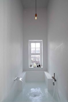 a white bathroom with a tub and window