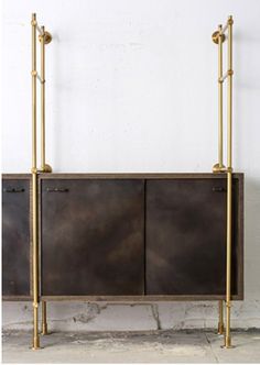 an iron and brass cabinet with two doors on the side, against a white wall