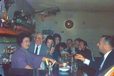 a group of people sitting at a table with drinks in front of them and smiling