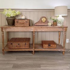 a wooden table with baskets on it and a clock sitting on top of it next to a lamp