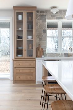 a kitchen with white counter tops and wooden cabinets next to a large open glass door