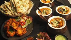 a table topped with lots of different types of food and bowls filled with sauces