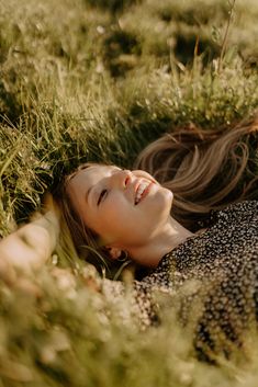 a woman laying in the grass with her eyes closed