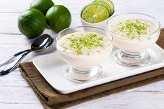 two desserts on a white tray with limes and spoons next to them