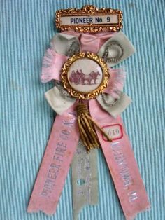 a pink ribbon with an animal on it and a name tag attached to the ribbon