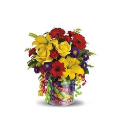 a vase filled with lots of colorful flowers next to ribbons and candies on a white background