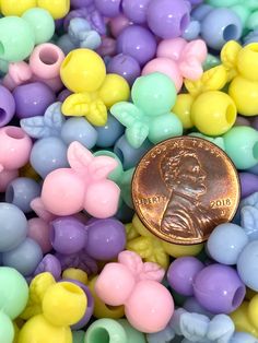 a penny sitting on top of a pile of small plastic beads in pastel colors