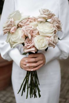 a woman holding a bouquet of white and pink roses