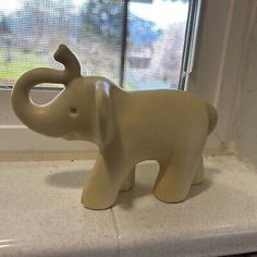 an elephant figurine sitting on top of a counter next to a window sill