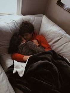 two people are sleeping on a couch together