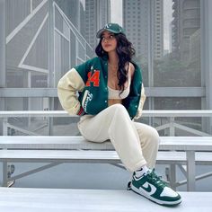 a woman sitting on top of a white bench in front of a cityscape