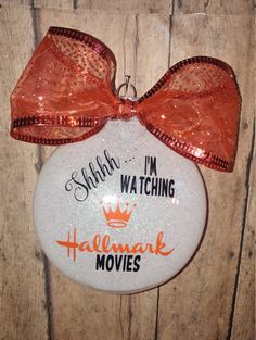 a white ornament with an orange bow on it that says i'm watching halloween movies