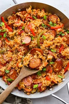 a skillet filled with rice, sausage and peppers