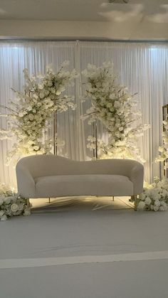 a white couch sitting in front of a wall with flowers and trees on top of it