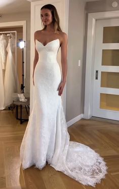 a woman in a white wedding dress standing on a wooden floor next to a mirror