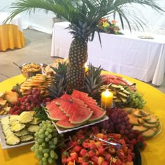 a table topped with lots of different types of fruits and veggies next to a candle