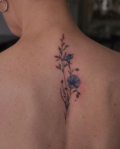 the back of a woman's shoulder with blue flowers on it