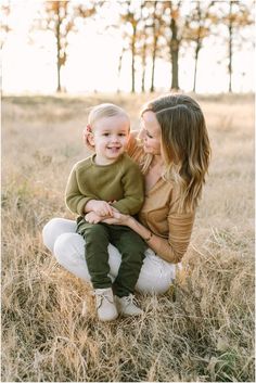 a mother and her child sitting in the grass