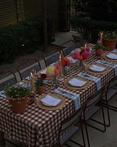 a table set up with place settings and flowers in vases on the sidelines