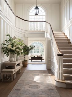 an elegant entryway with stairs and vases filled with flowers