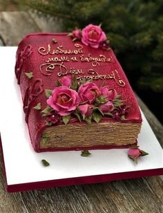 a red book decorated with pink flowers on top of a wooden table next to a tree