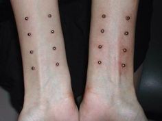 two people with matching tattoos on their arms and legs, both have small dots in them