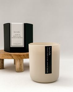 a white candle sitting on top of a wooden table next to a black and white box