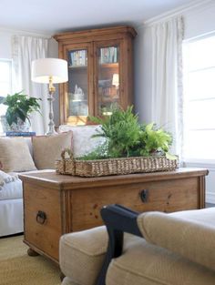 a living room filled with furniture and a basket on top of a table in front of a window