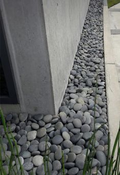 some very pretty rocks by the side of a building with grass growing in front of it